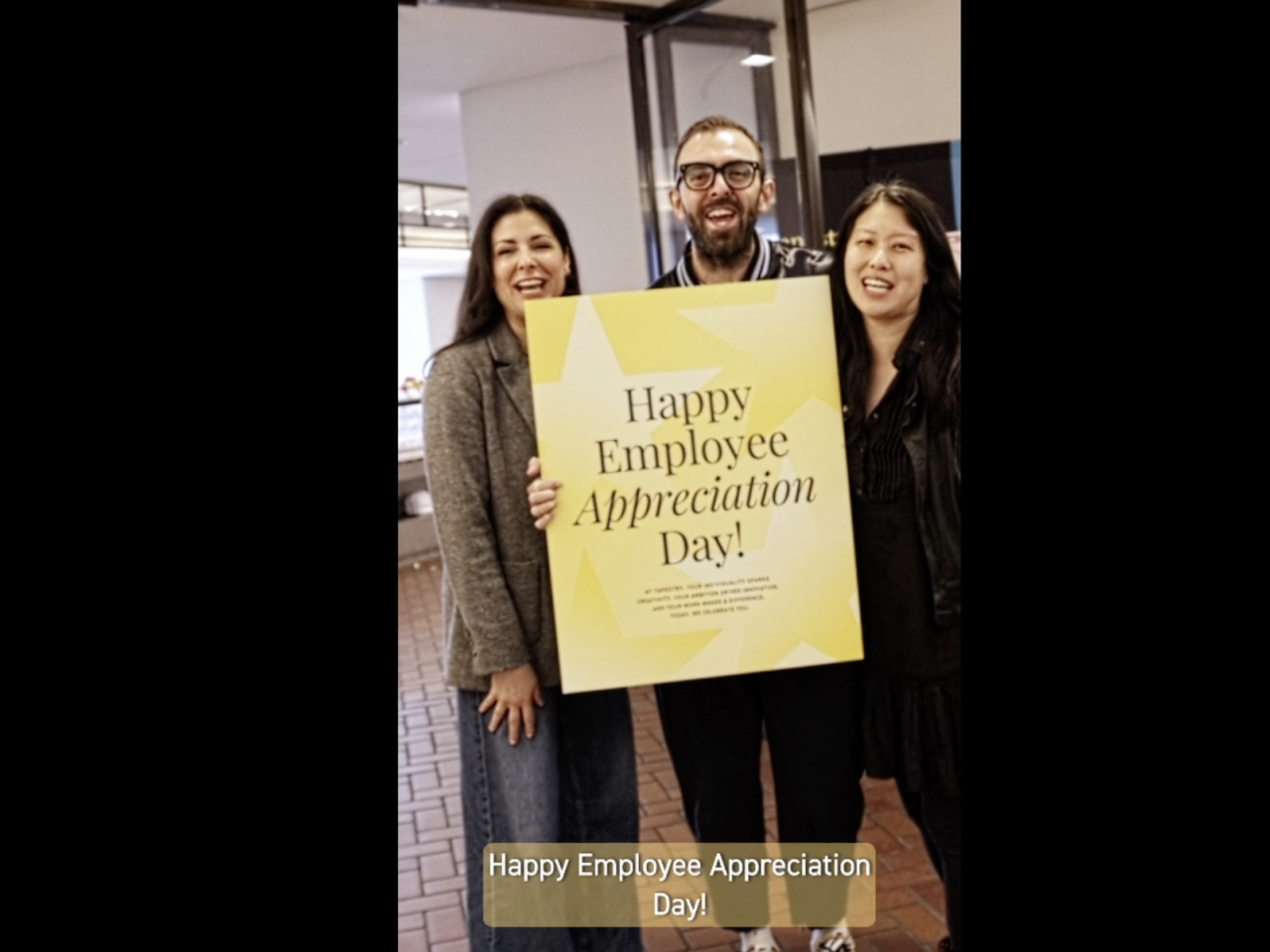 Tapestry employees holding employee appreciation day sign