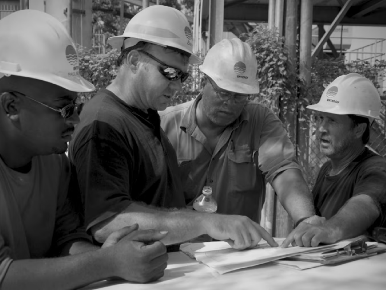 4 people in hardhats looking at papers