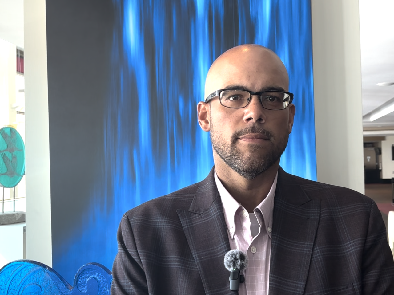 Man wearing glasses in front of backdrop