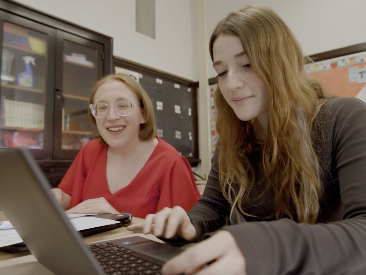 Educator and student working on a laptop