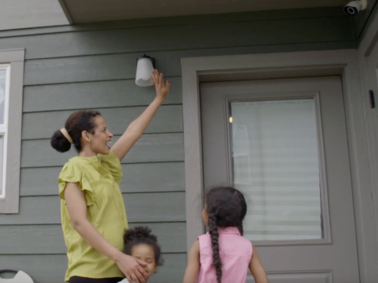 Family standing by front door waving at camera