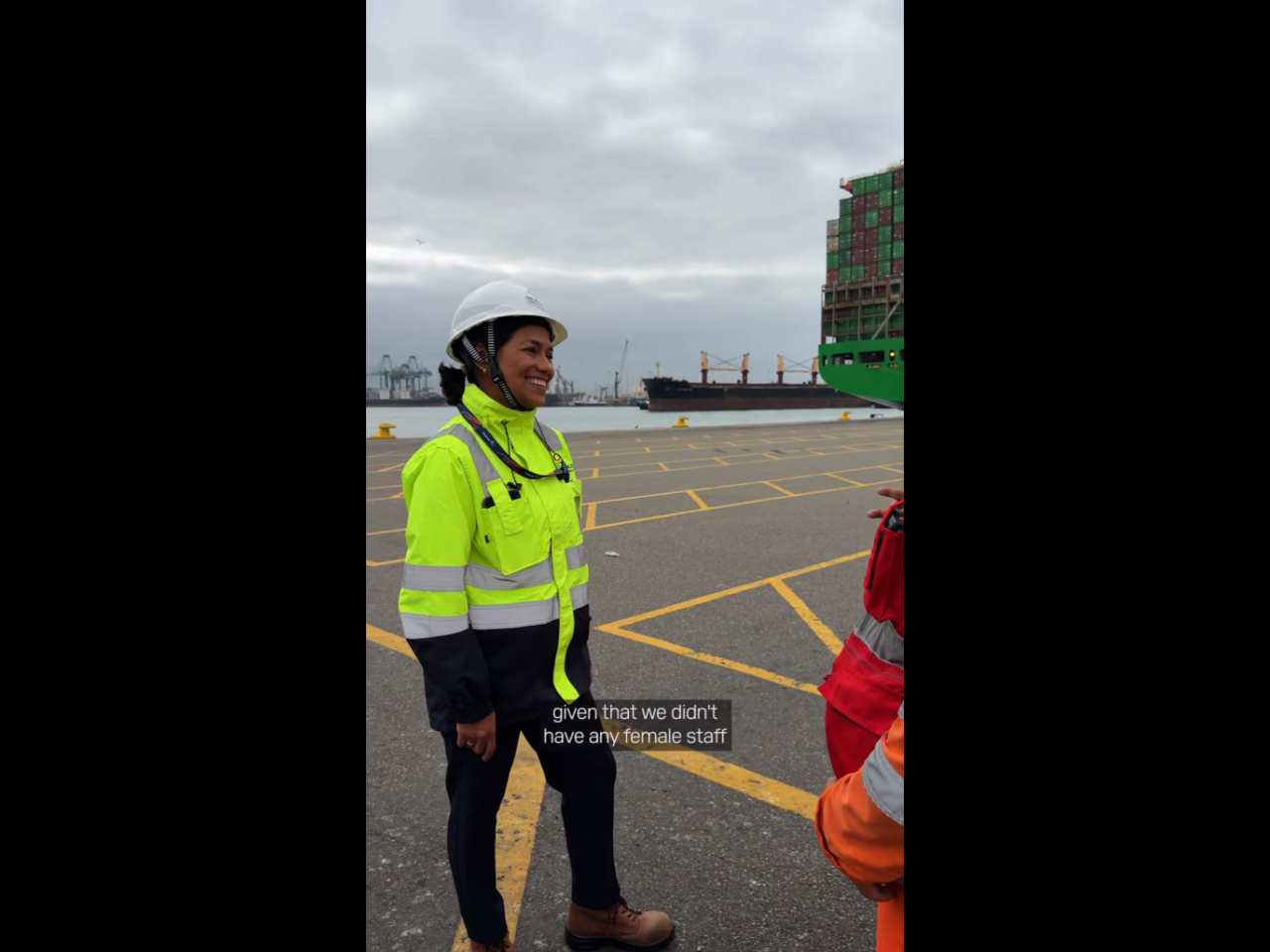 Cynthia Garrido, wearing a hard hat and high-visibility PPE, speaks with colleagues at DP World's container terminal in Callao, Peru