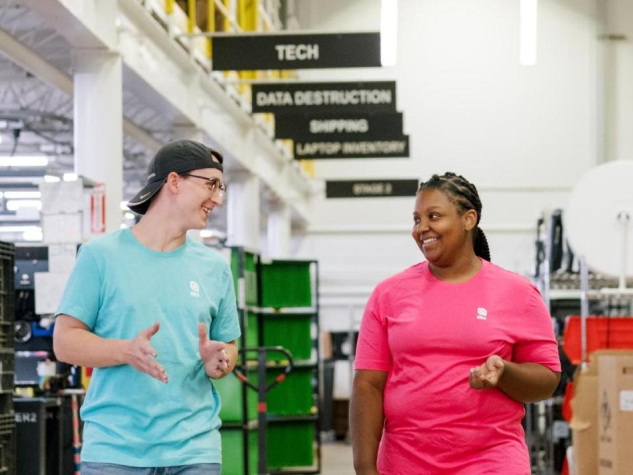 Two smiling people talking and walking inside a building