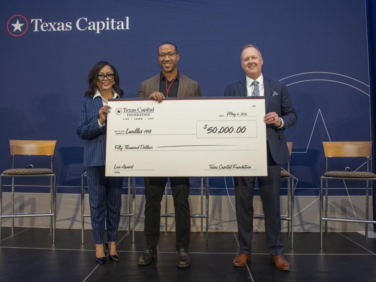 Three people holding a large check