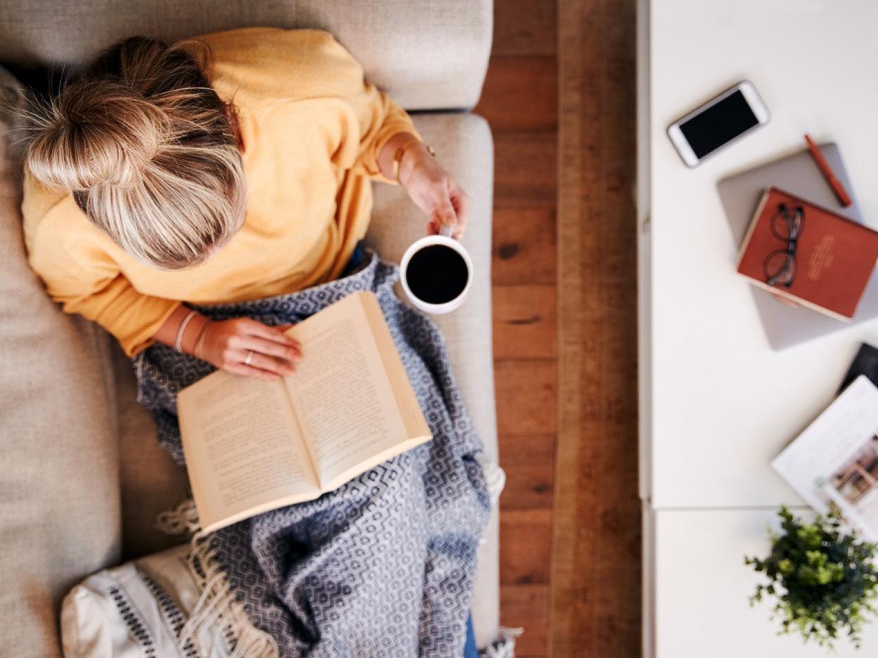 Aerial view of a woman reading a book on a couch