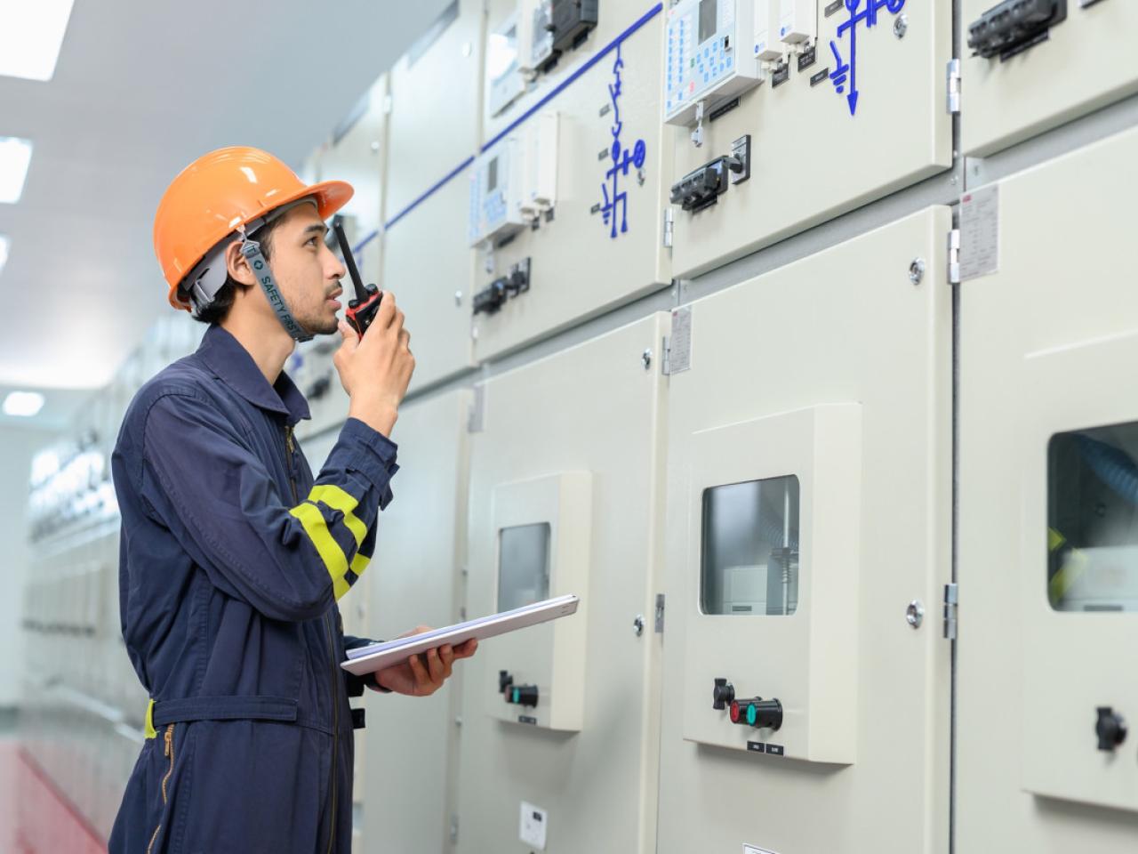 Facility worker in PPE speaking into a radio