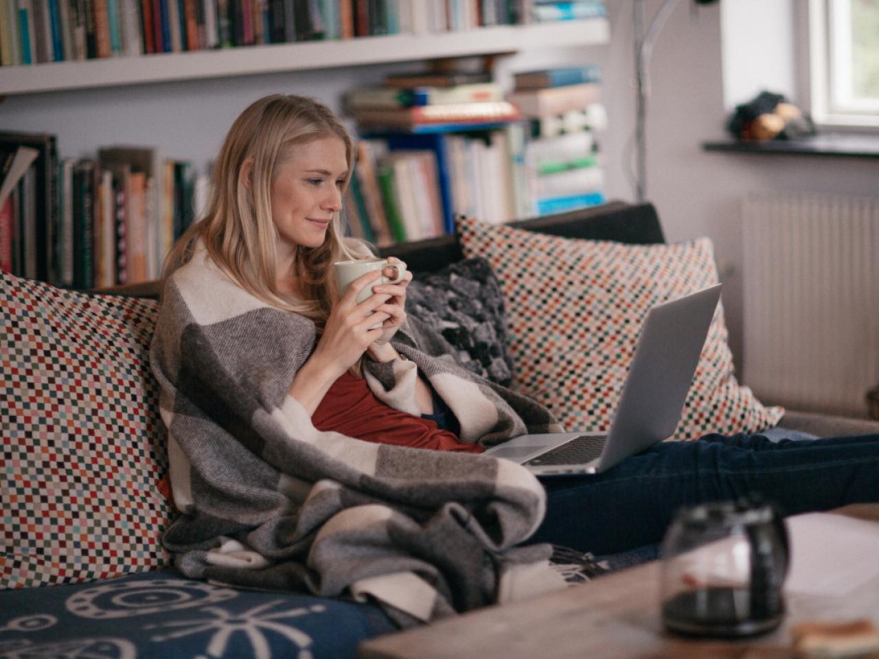 Woman sitting on a couch watching a show on her laptop