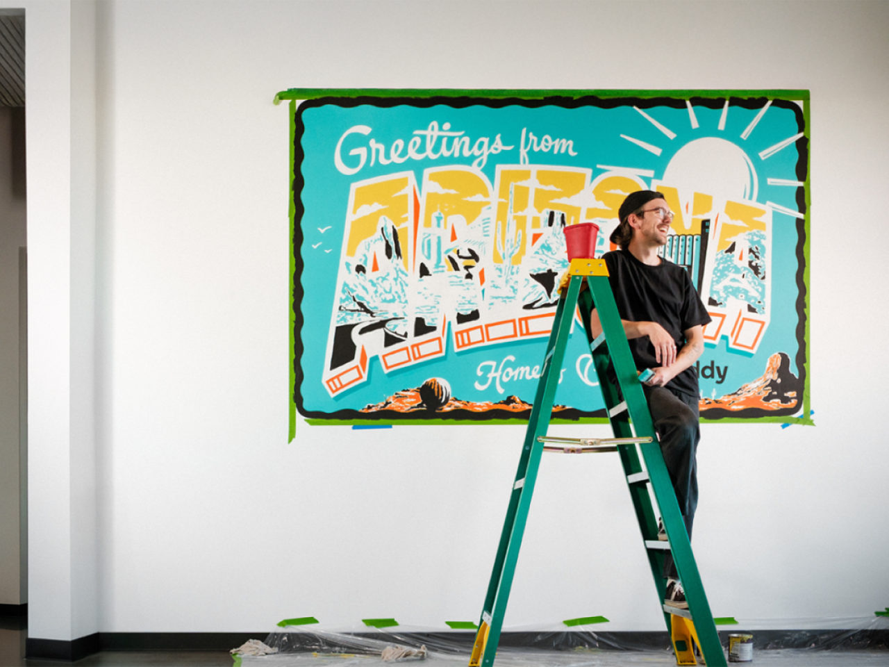 person smiling while standing on a short ladder