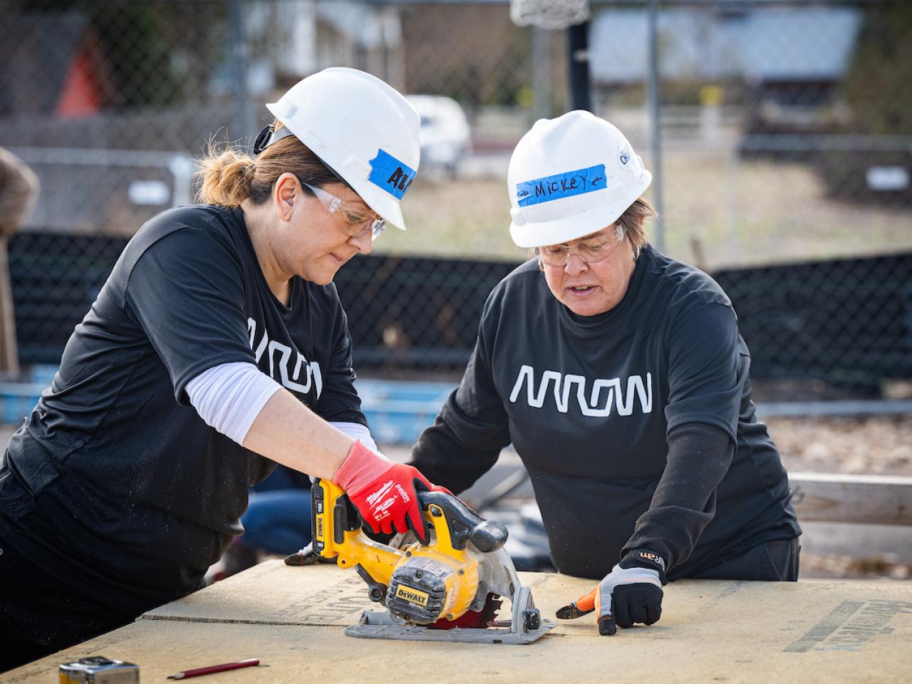 2 arrow employees using a saw