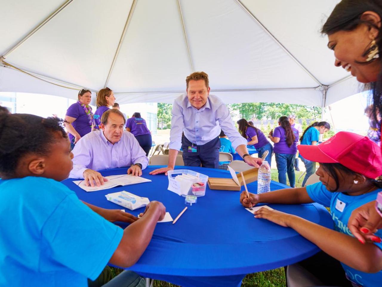 CEO stands over table teaching students