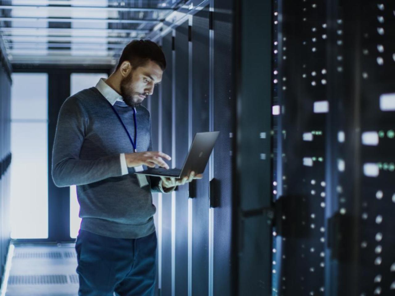 A man in a data center with a laptop.