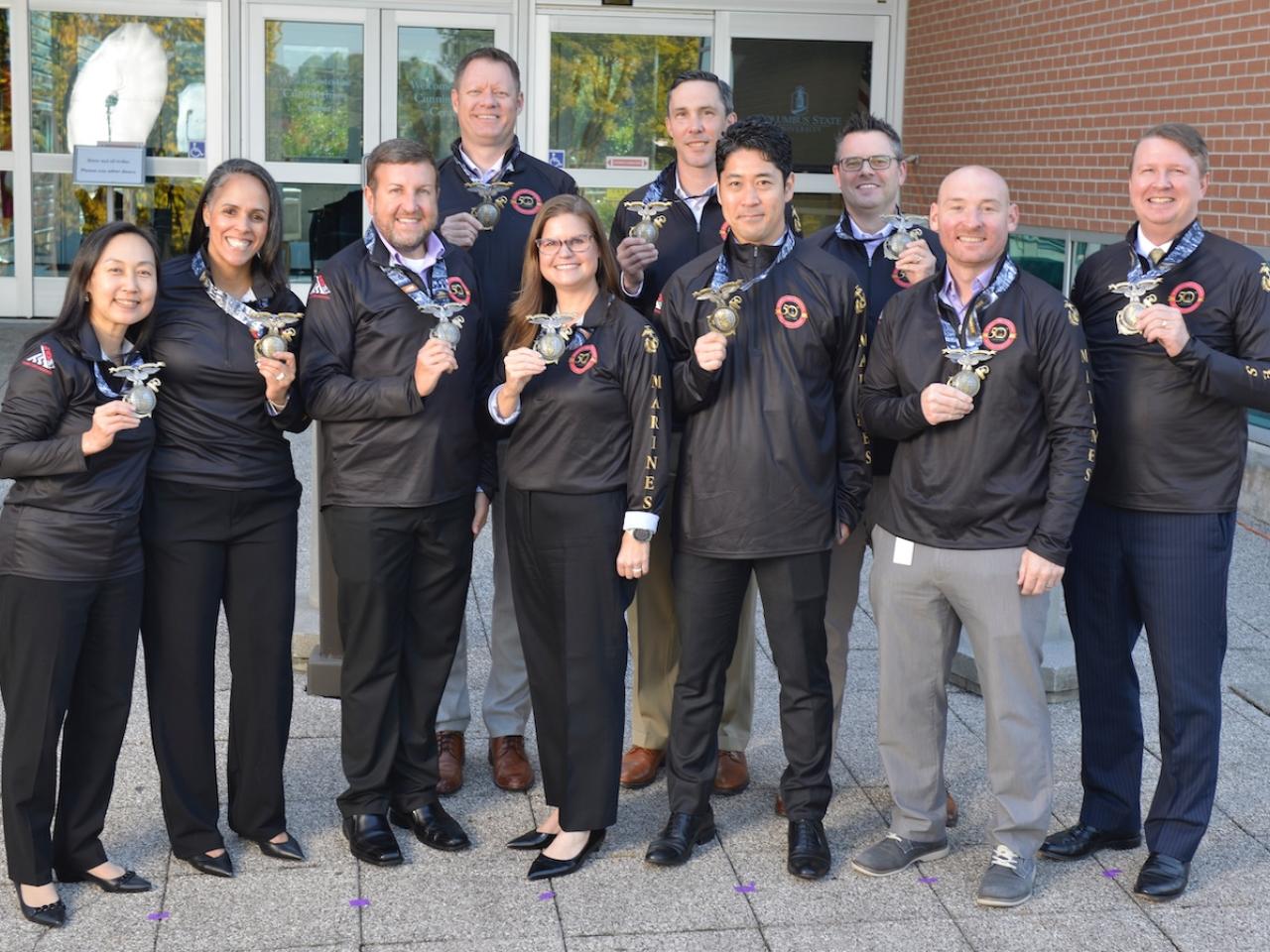 Aflac team members show their medals from the Marine Corps Marathon.