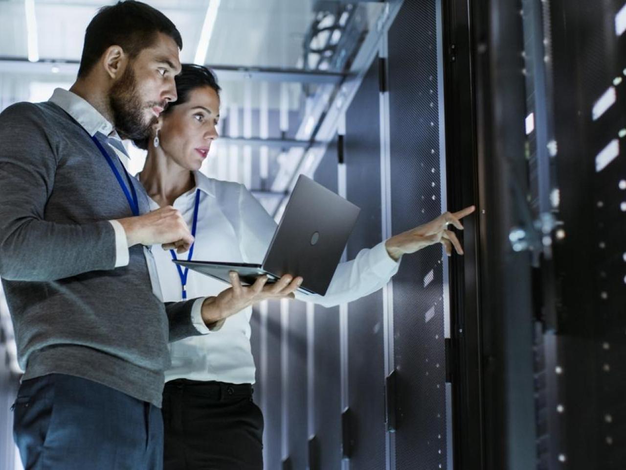 Two workers looking at a data center system