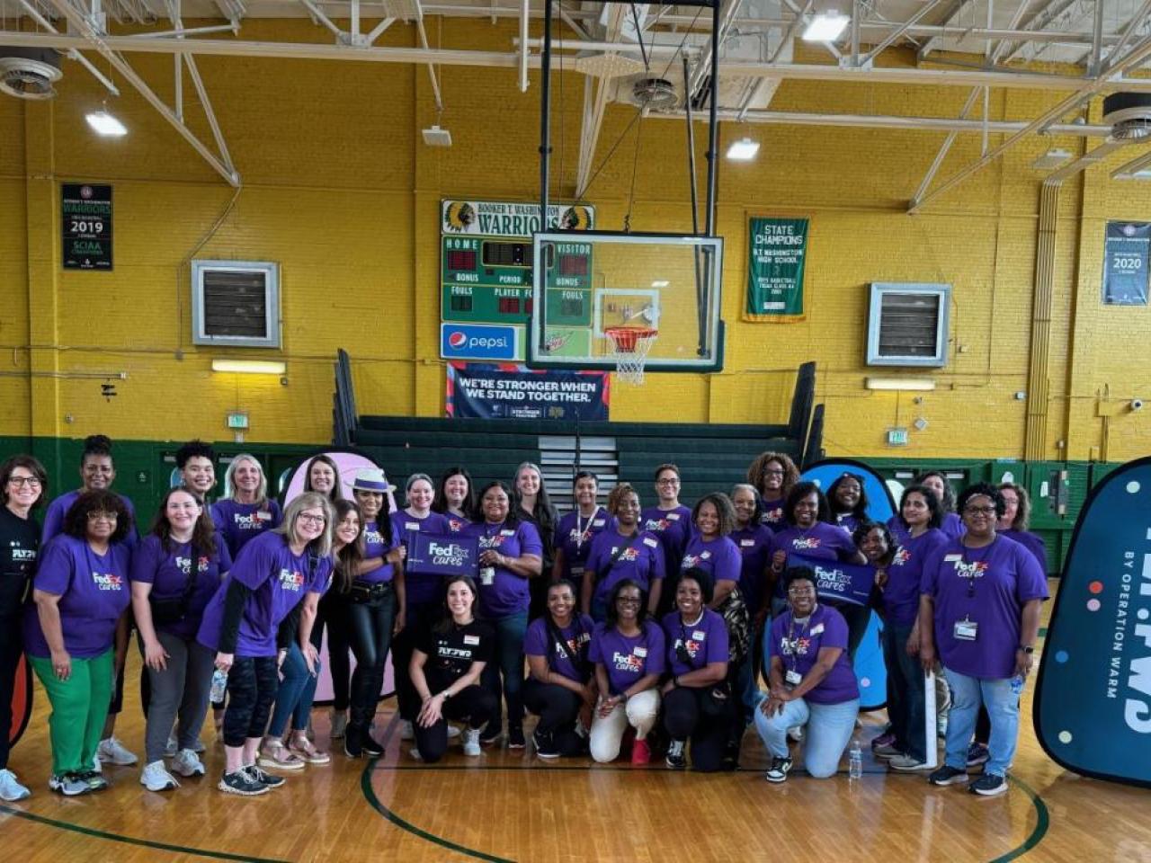 Female athletes wearing FedEx shirts standing together in gym