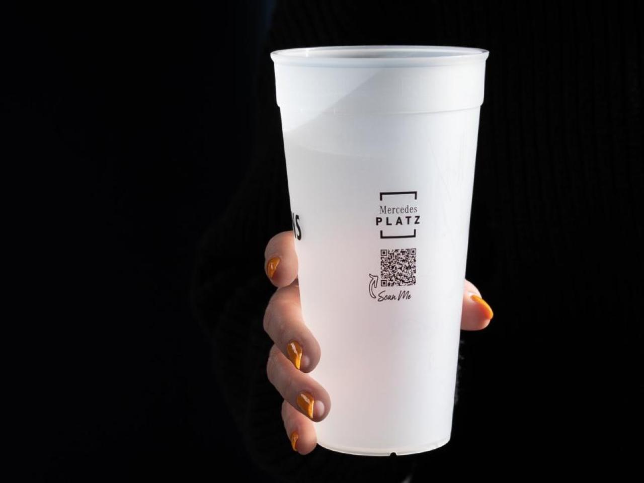 Hand holding reusable cup from Mercedes-Benz Arena.