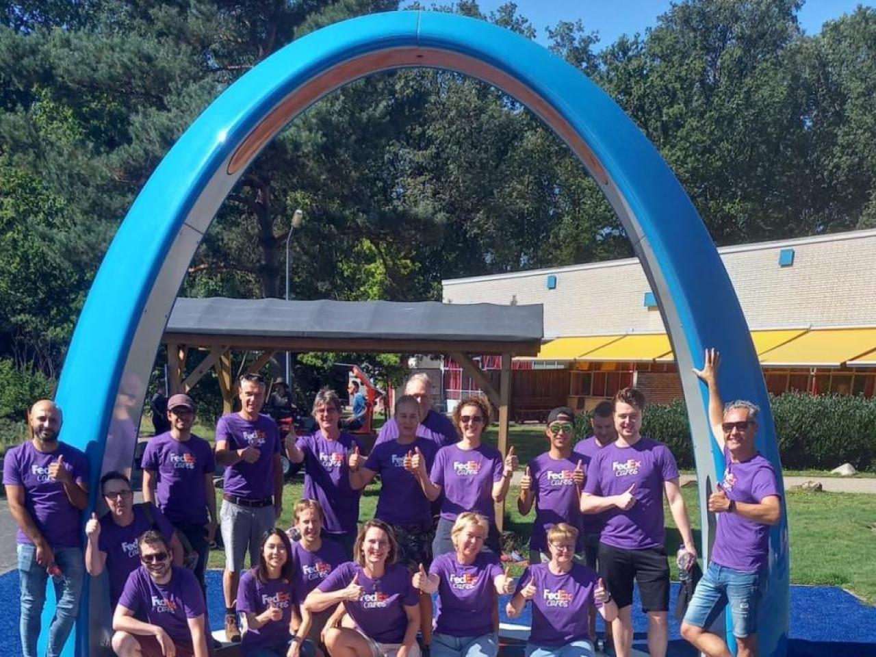 Volunteers posed in front of a large blue arch outside.