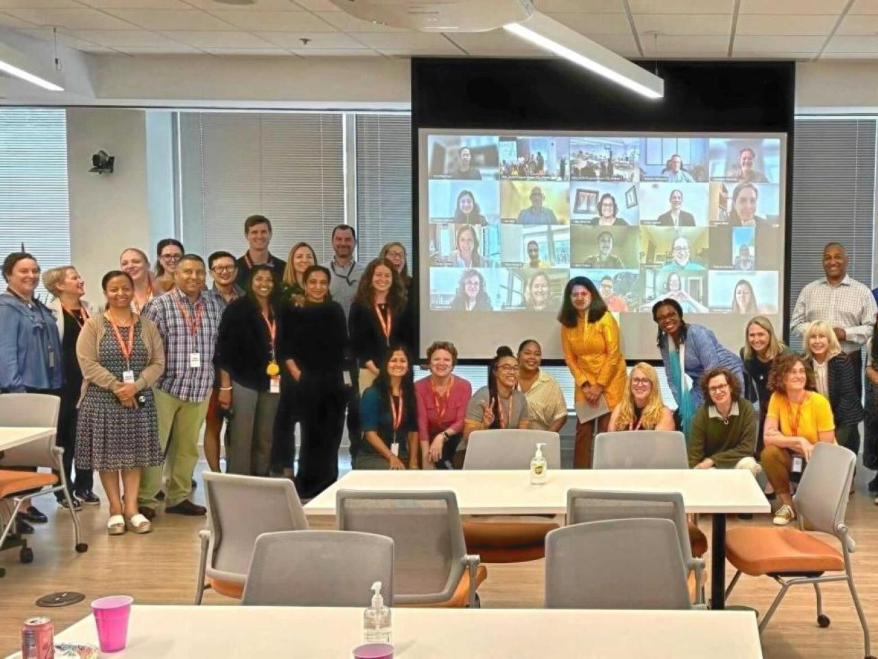 photo of team group standing in front of a screen