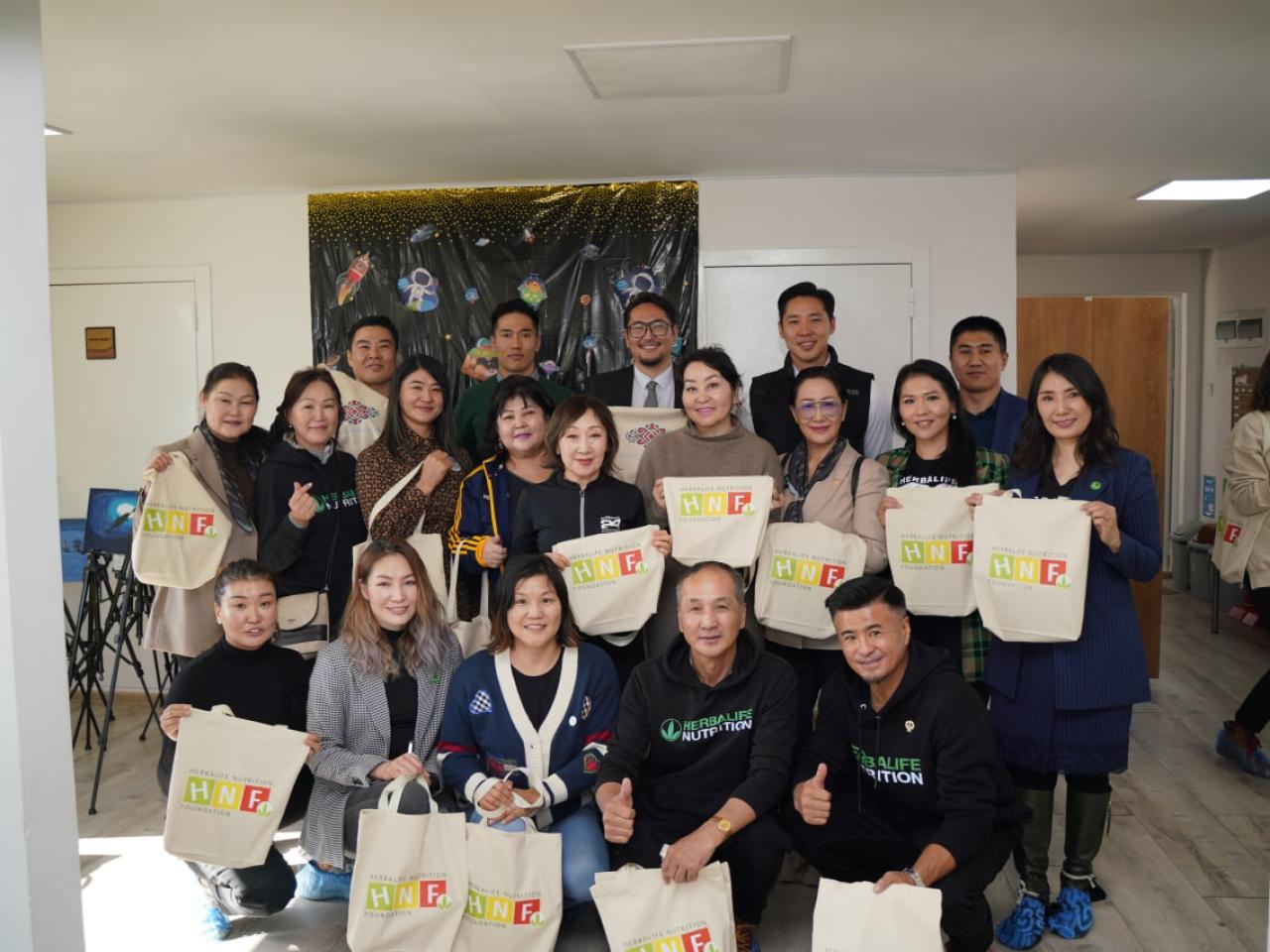Group of people holding Herbalife Nutrition Foundation tote bags