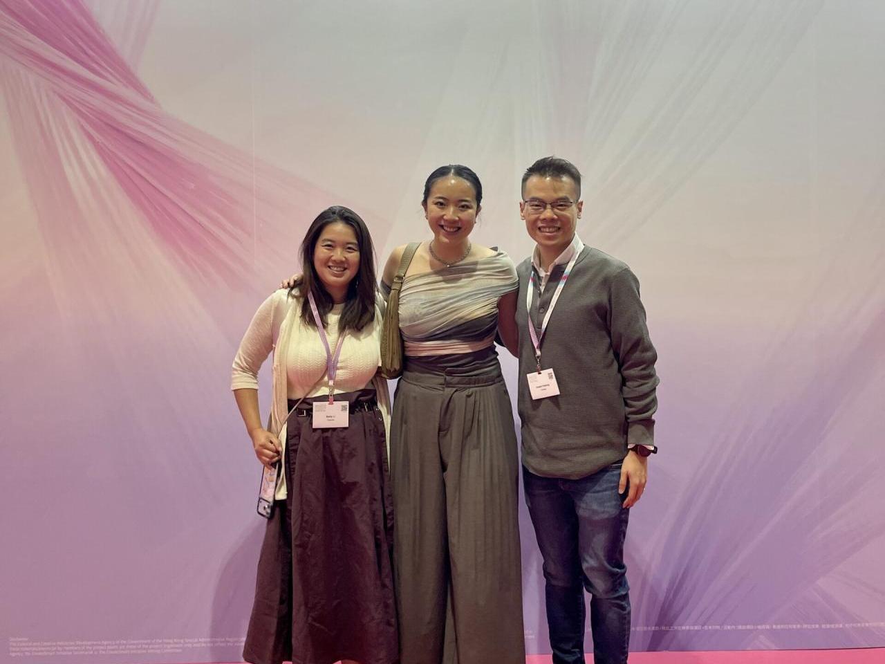 Three people on a stage, red carpet
