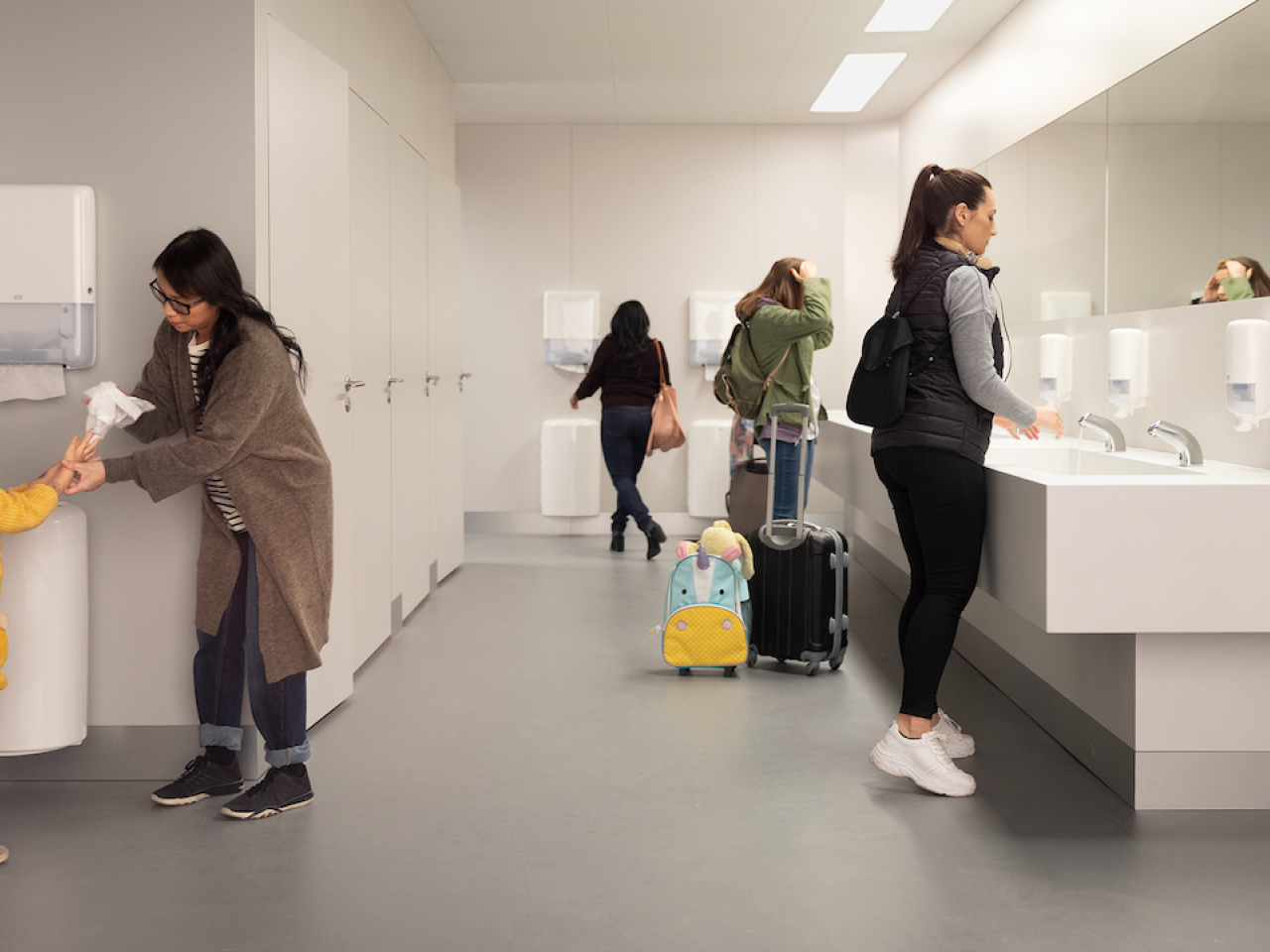 Group of people washing their hands in a restroom. 