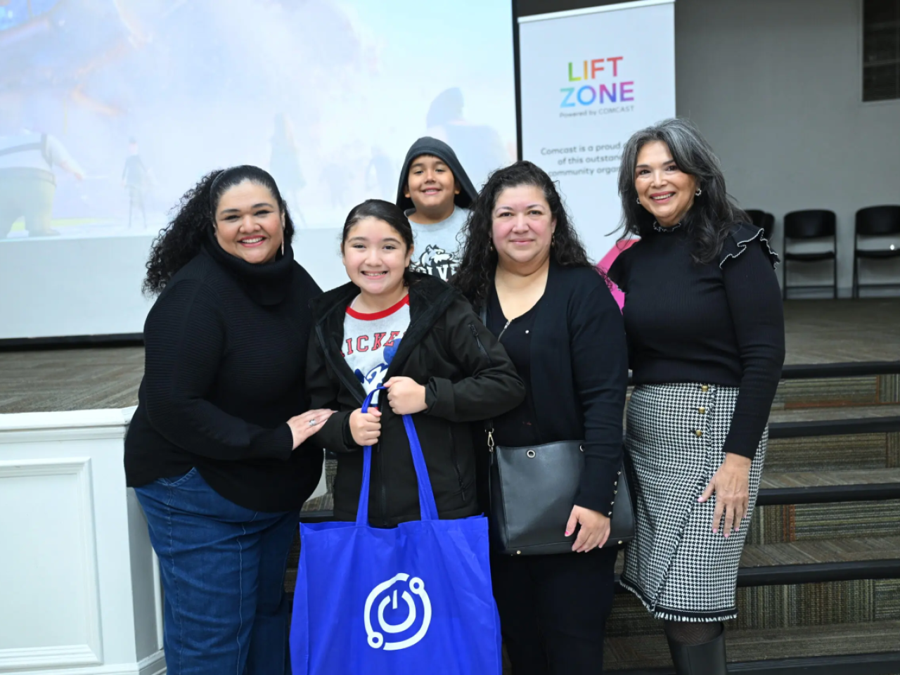 Group photo centering a student who is holding a bag containing the tech tools needed to connect her home to the internet