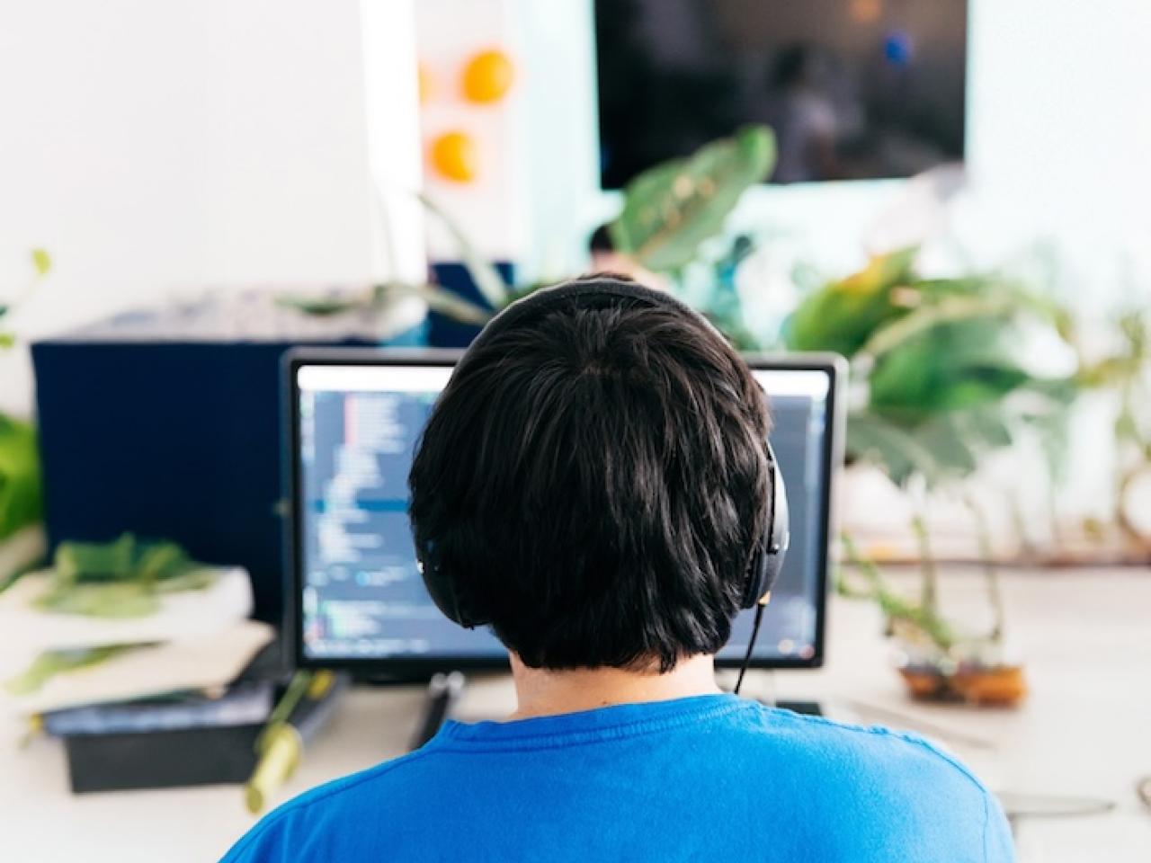 Operator seated behind a desktop computer wearing headphones.