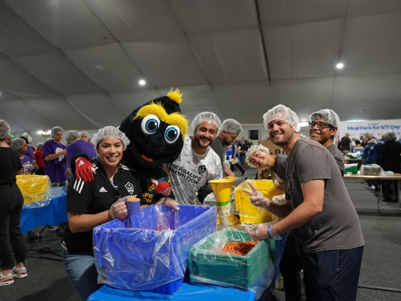 LA Galaxy's mascot Cozmo helps pack meals with volunteers from LA Galaxy.