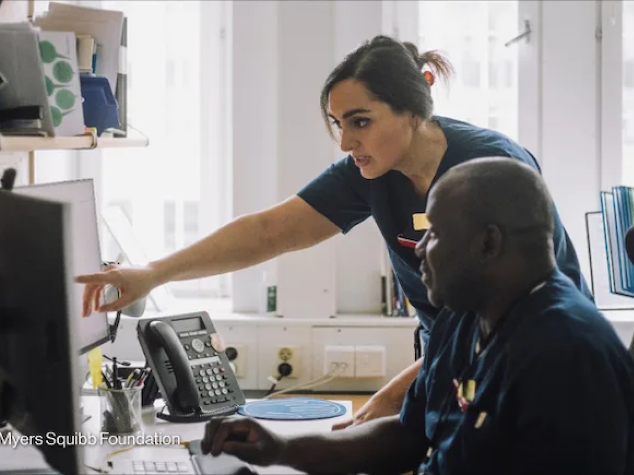 Health care workers consult their notes in a clinic. Photo by: The Bristol Myers Squibb Foundation