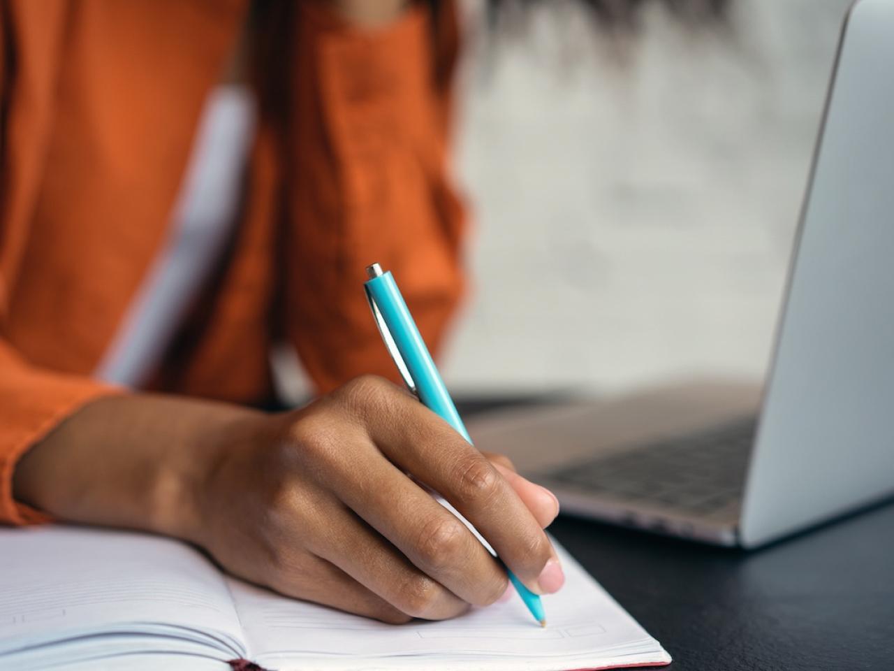 Person shown writing in a notebook.