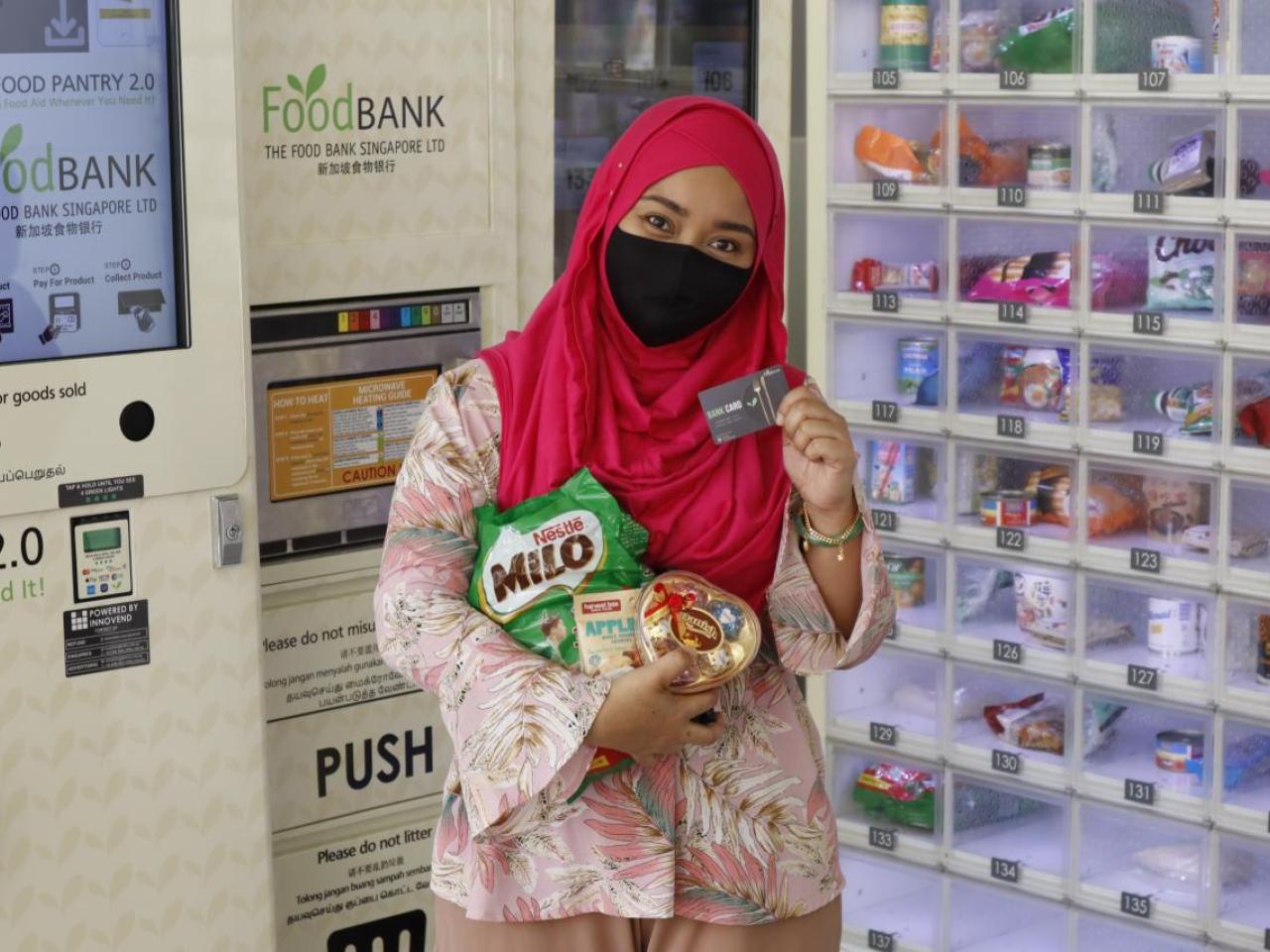 Woman holding up her food bank card