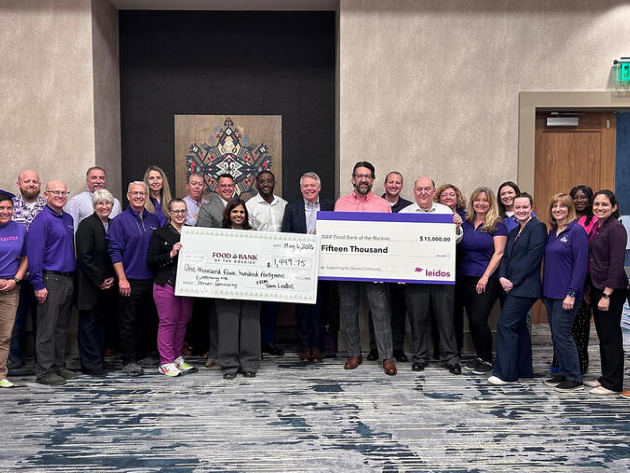 Group photo with two large checks on display for the food bank
