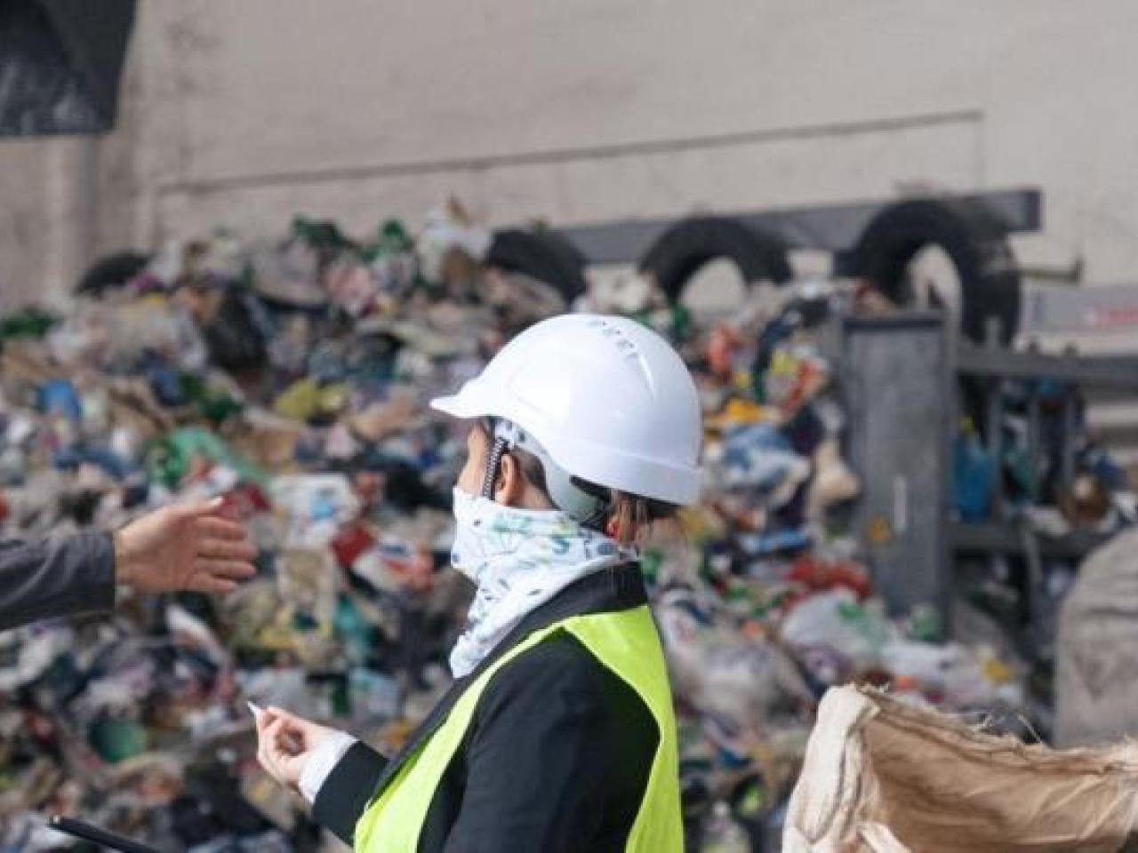 Two workers speaking in front of a landfill