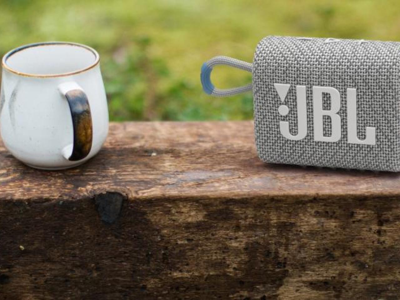 Coffee cup and JBL speaker shown in a grassy field.
