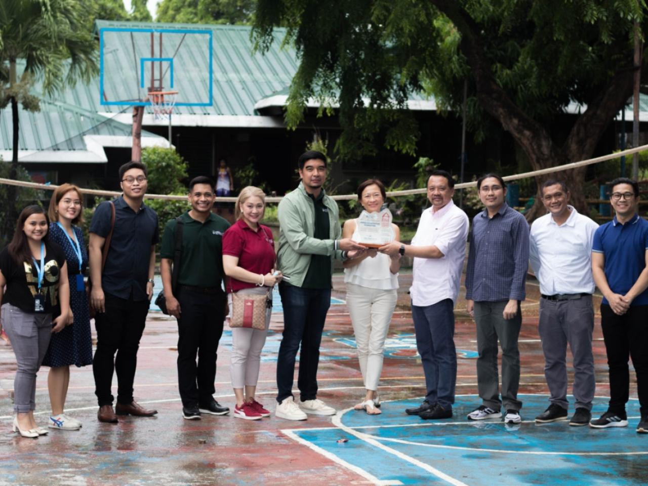 a group of people on a basketball court, three holding an award