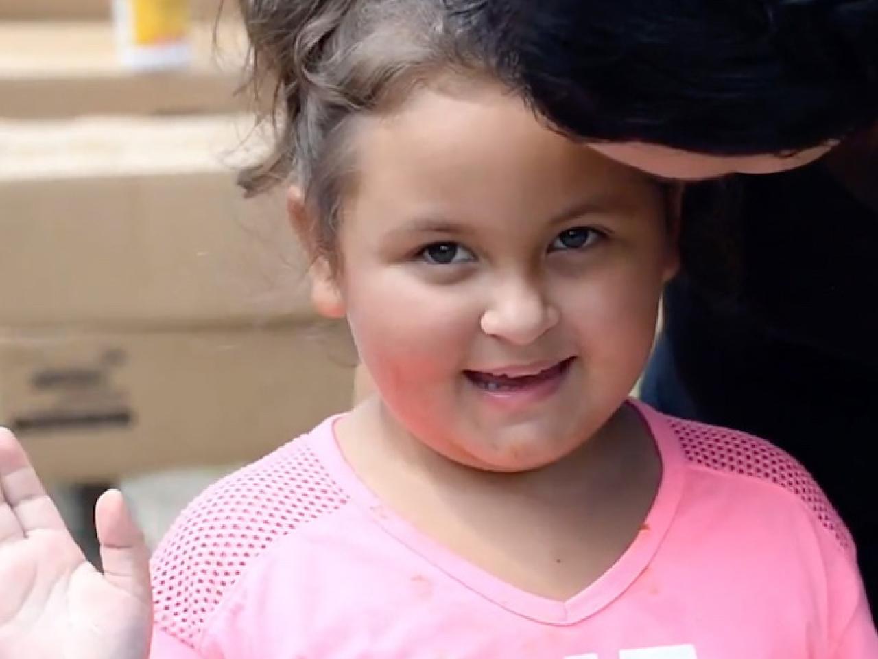 Young girl smiling and waving.
