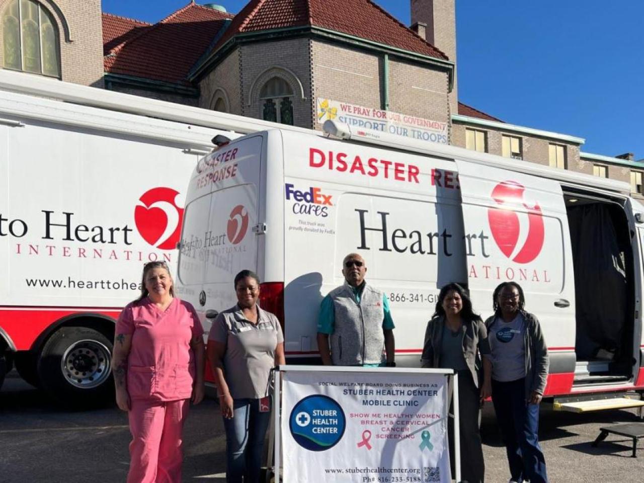 Group photo in front of Heart to Heart van and truck