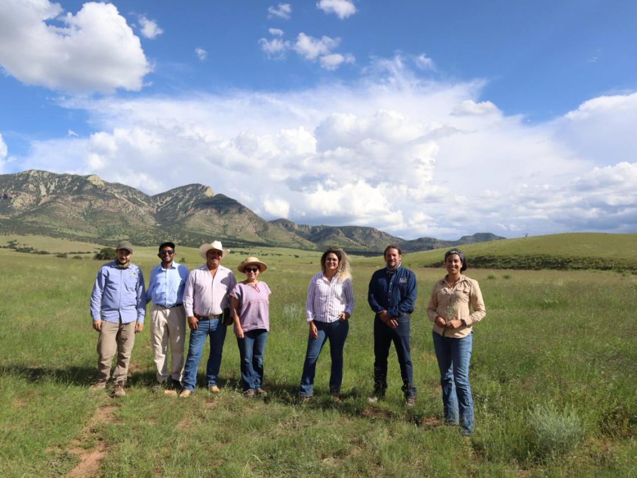 Boomitra staff and stand in a grasslands field with local ranchers 