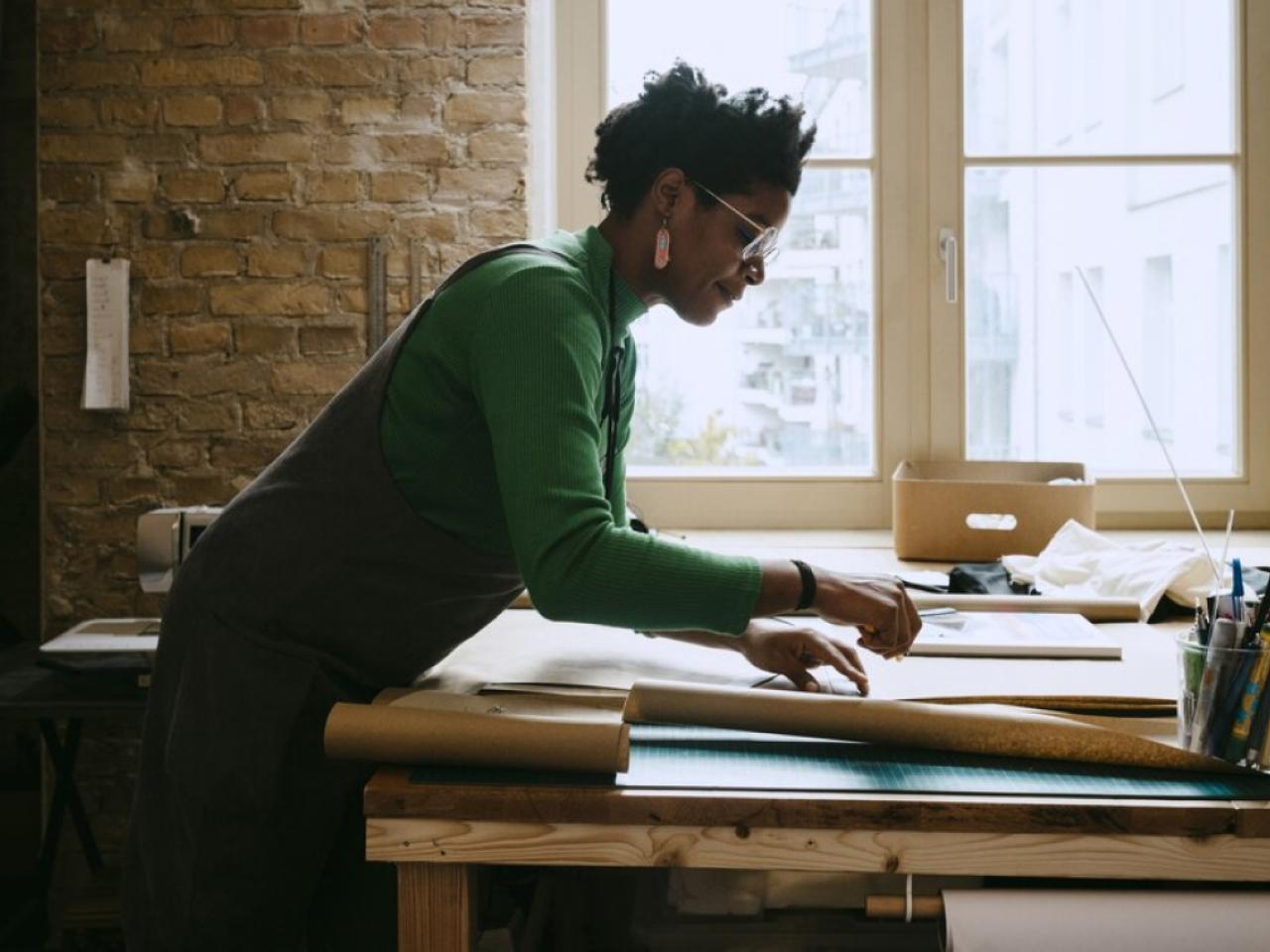 Woman shown standing at a desk reviewing paperwork.