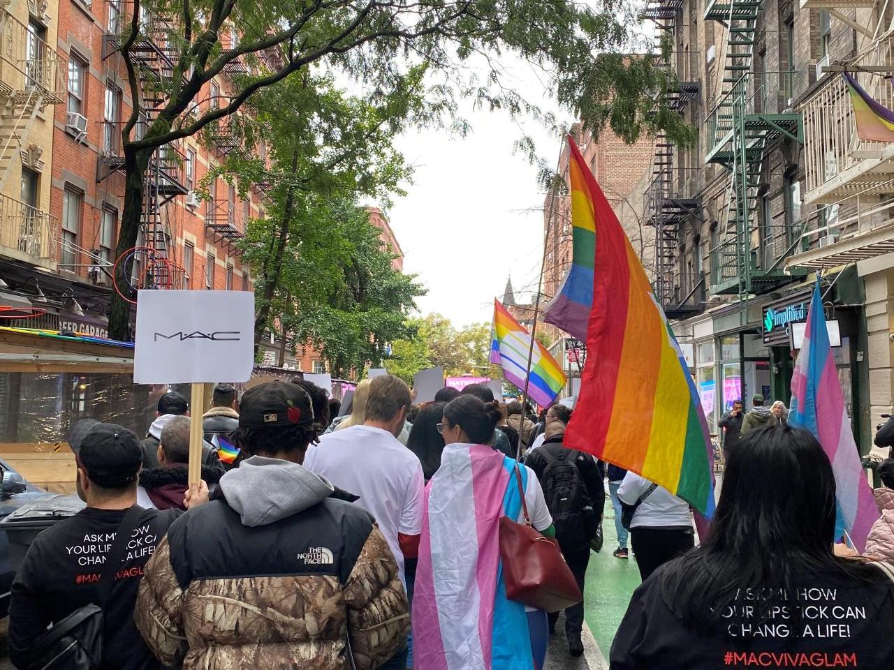 People marching down the street with signs and flags.