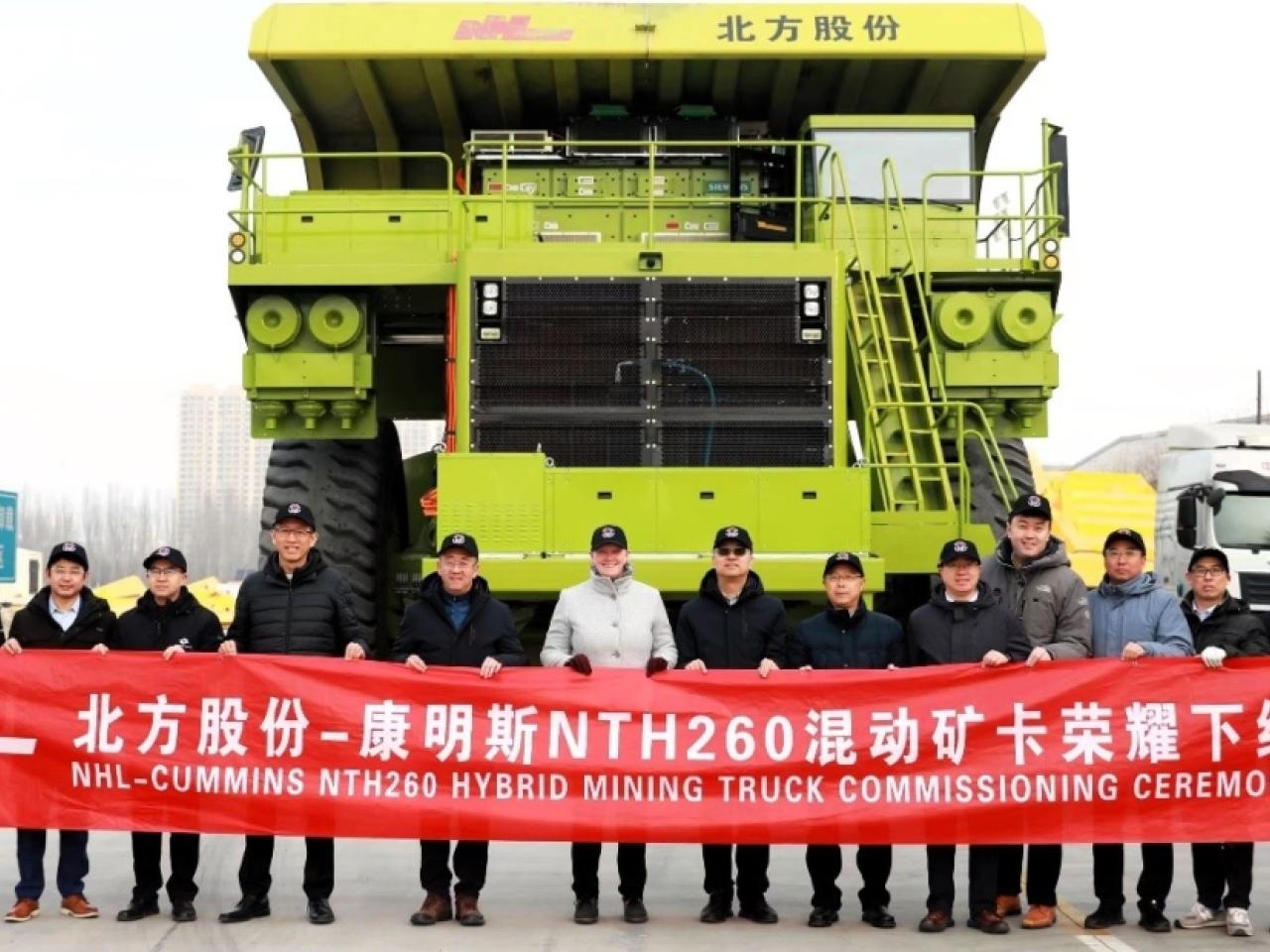 A line of people holding a line banner in front of a mining truck