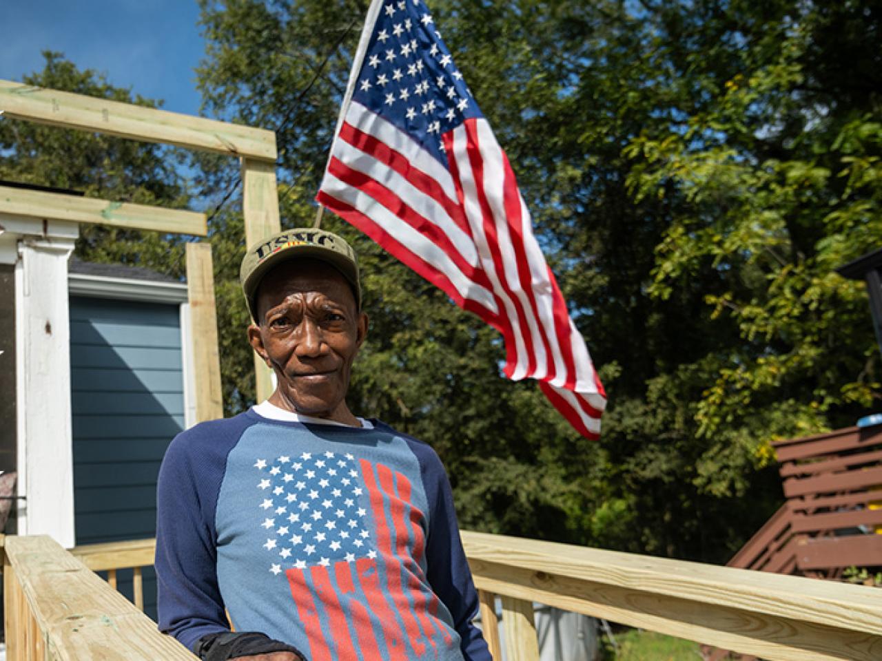 Operation Surprise: A Veteran shown in front of his home with an American flag waving in the background.