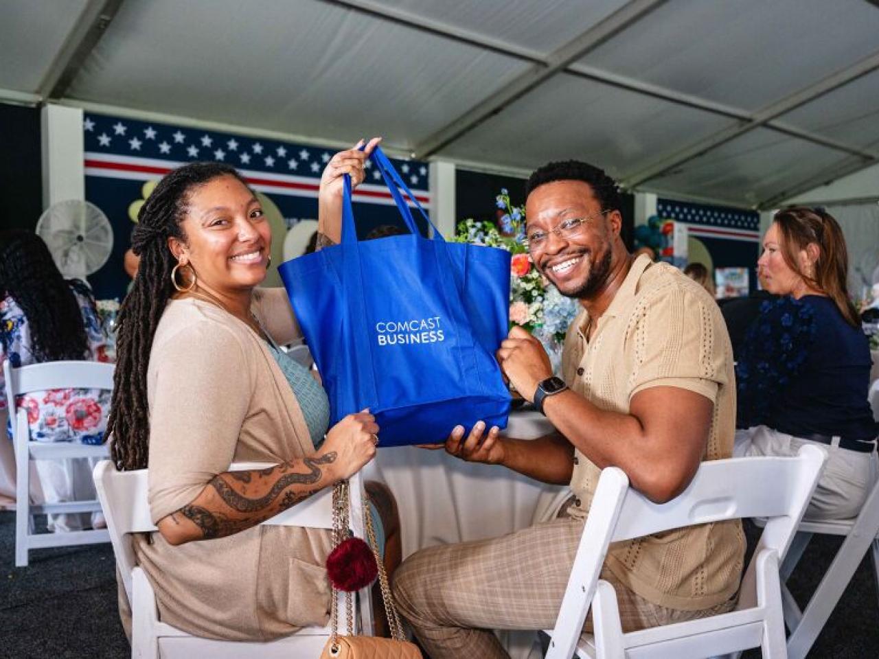 Couple holding up a "Comcast Business" bag at the Operation Shower event 