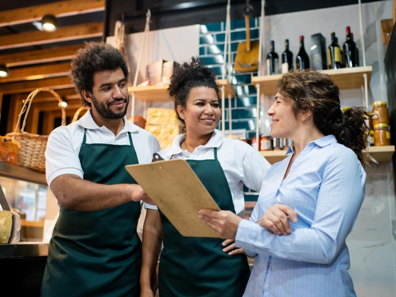 Three retail workers reviewing notes on a clipboard