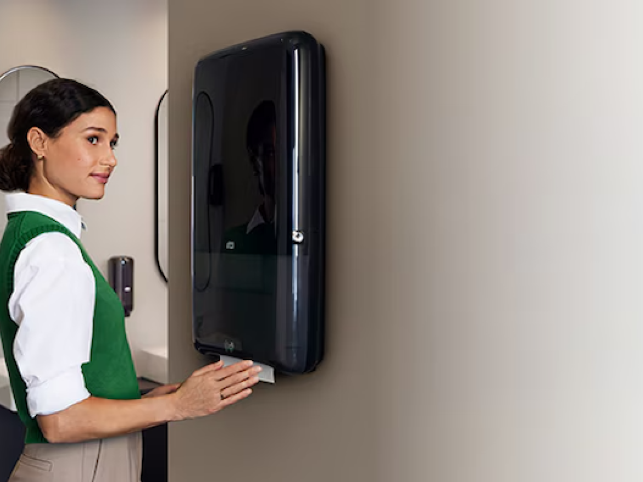 A person shown at a paper towel dispenser.