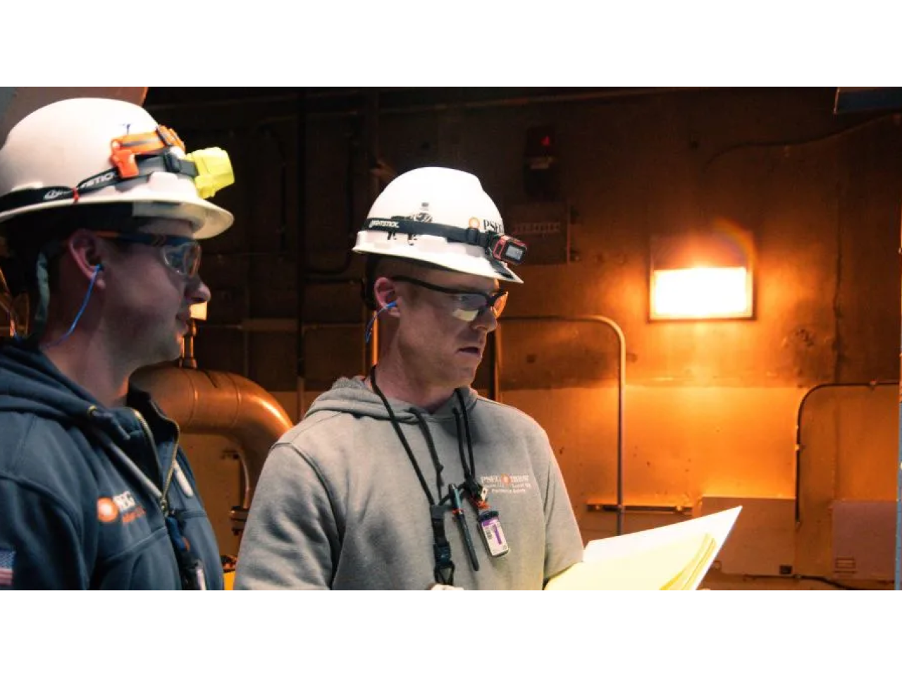 Two people wearing hard hats working in power plant
