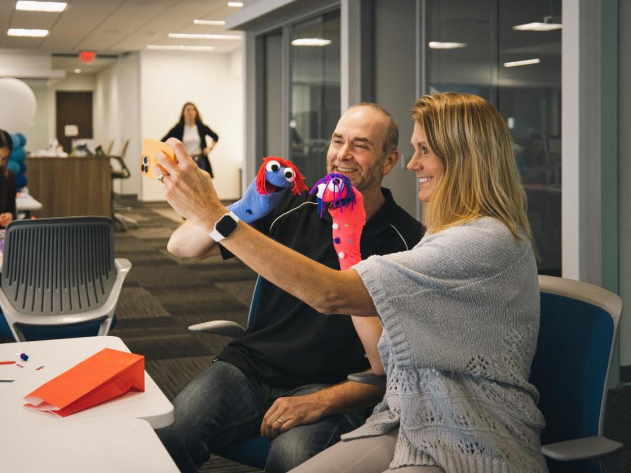 Woman and a man taking a selfie at a desk.
