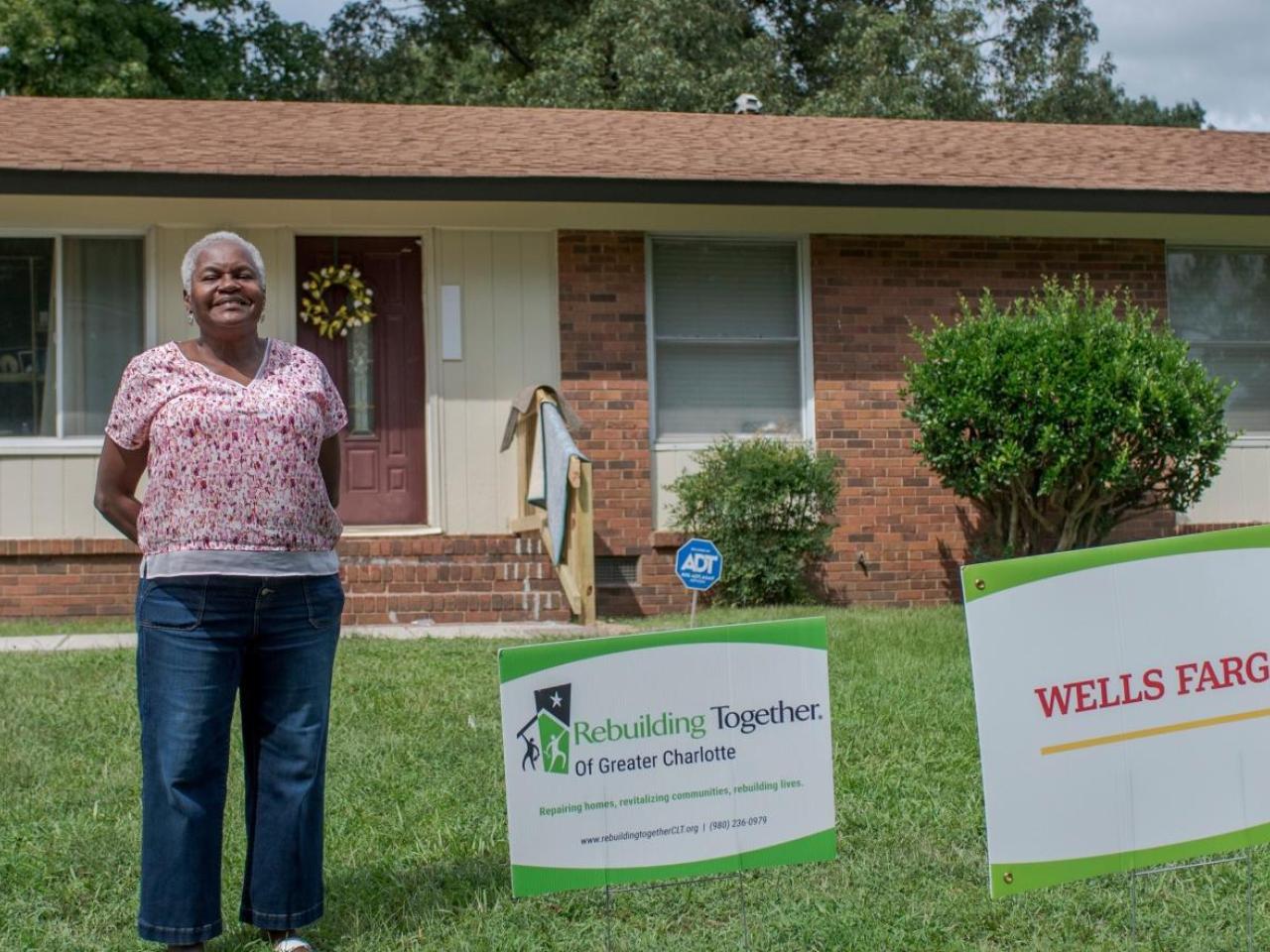 Woman stands in front of her house.
