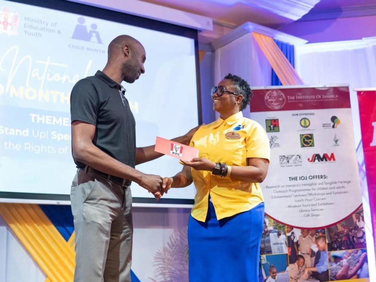 Restaurants of Jamaica Brand Manager Andrei Roper (left) presents a symbolic cheque to National Child Month Committee Chairperson Nicole Patrick-Shaw, during the National Child Month Launch.