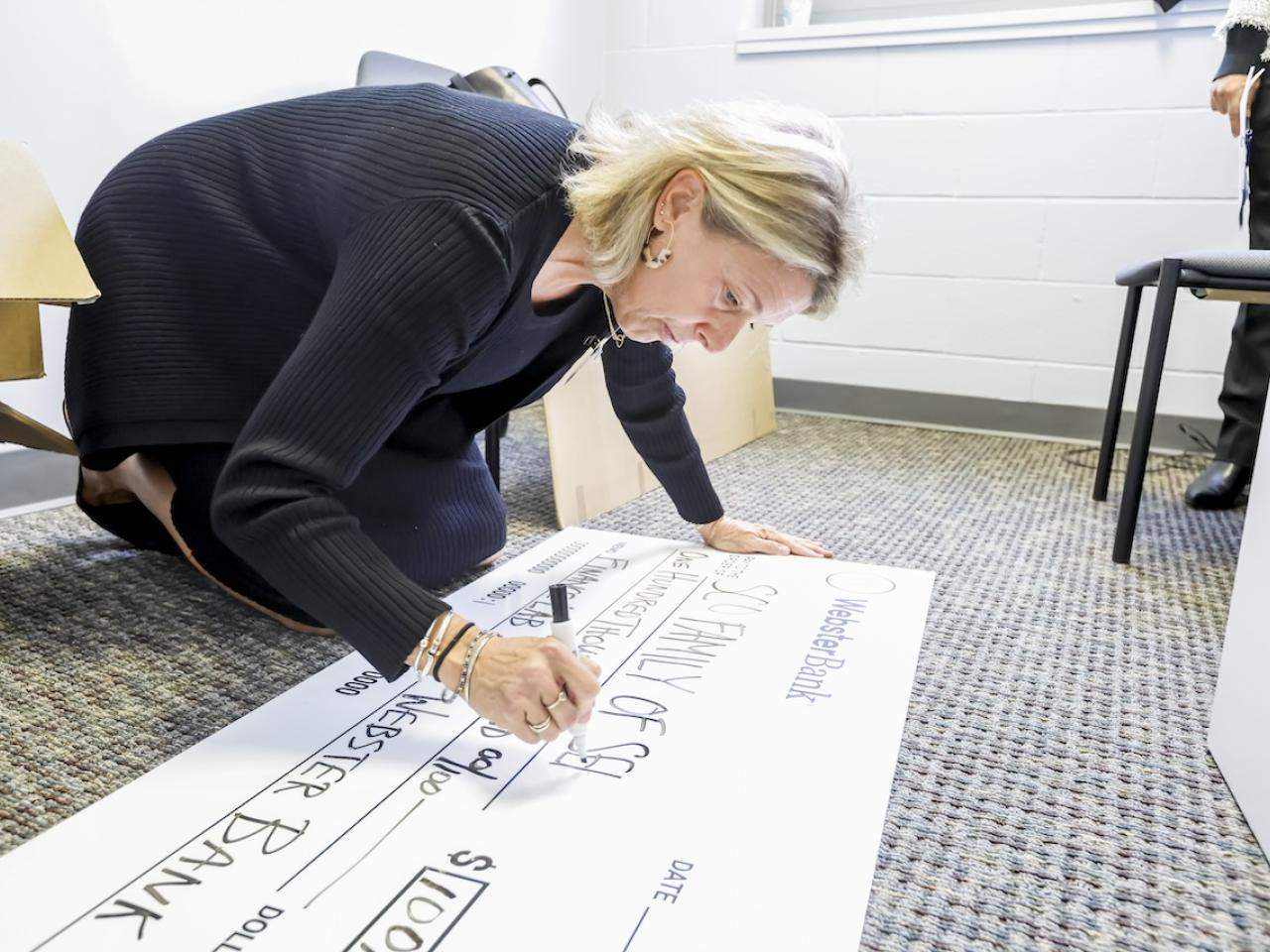 Grant check for $100,00.00 being made out by a representative from Webster Bank.