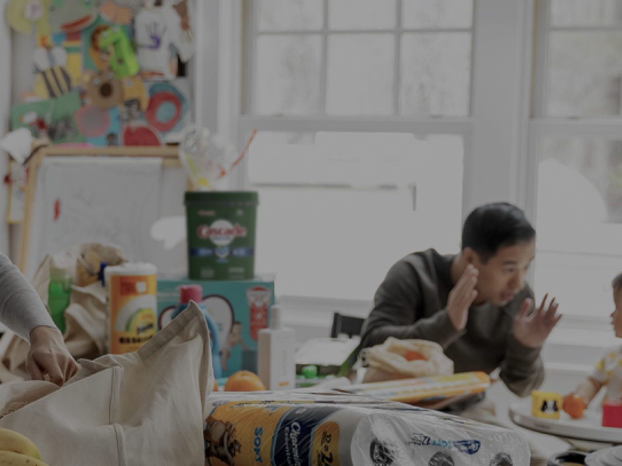 people in a kitchen unpacking a shopping bag